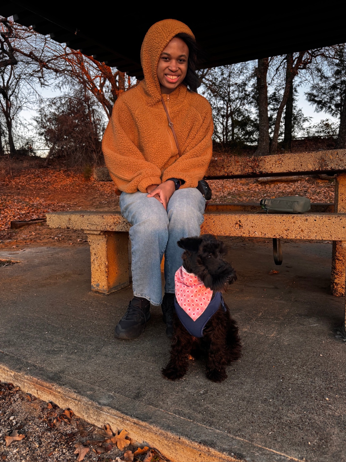 Kyra at a park bench with a small black dog