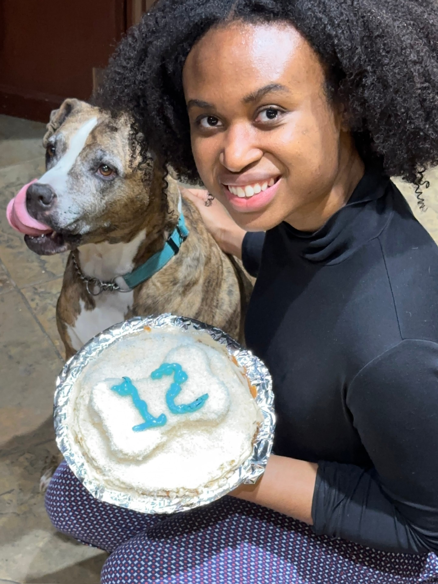 Kyra smiling next to a dog celebrating his 12th birthday with a homemade cake
